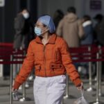 A nurse wearing a face mask to help curb the spread of the coronavirus walks by people lining up for a coronavirus test at a hospital in Beijing, Sunday, Jan. 17, 2021. The coronavirus was found on ice cream produced in eastern China, prompting a recall of cartons from the same batch, according to the government. (AP)